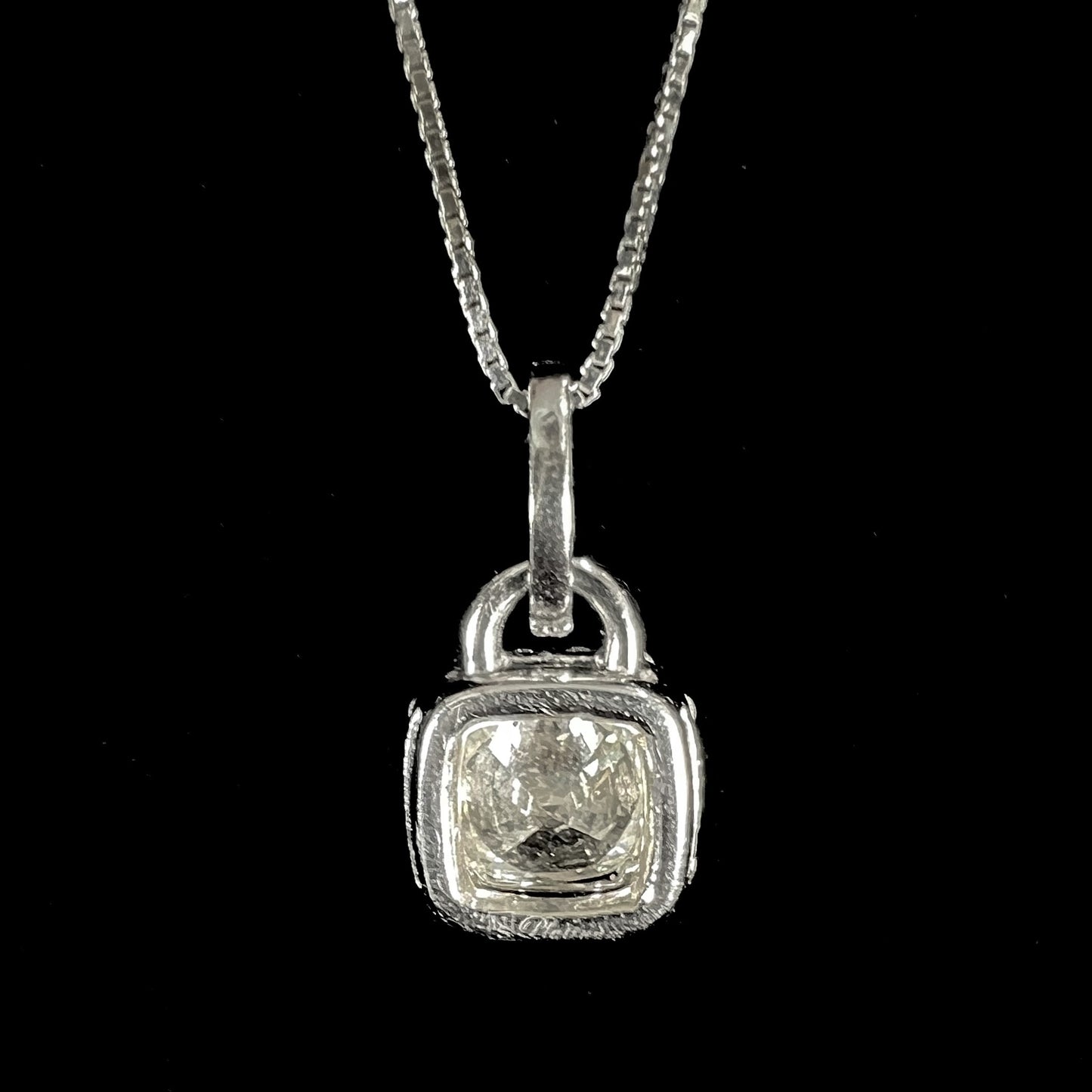 A ladies' platinum diamond halo necklace set with a 0.58ct cushion cut diamond on a box chain.