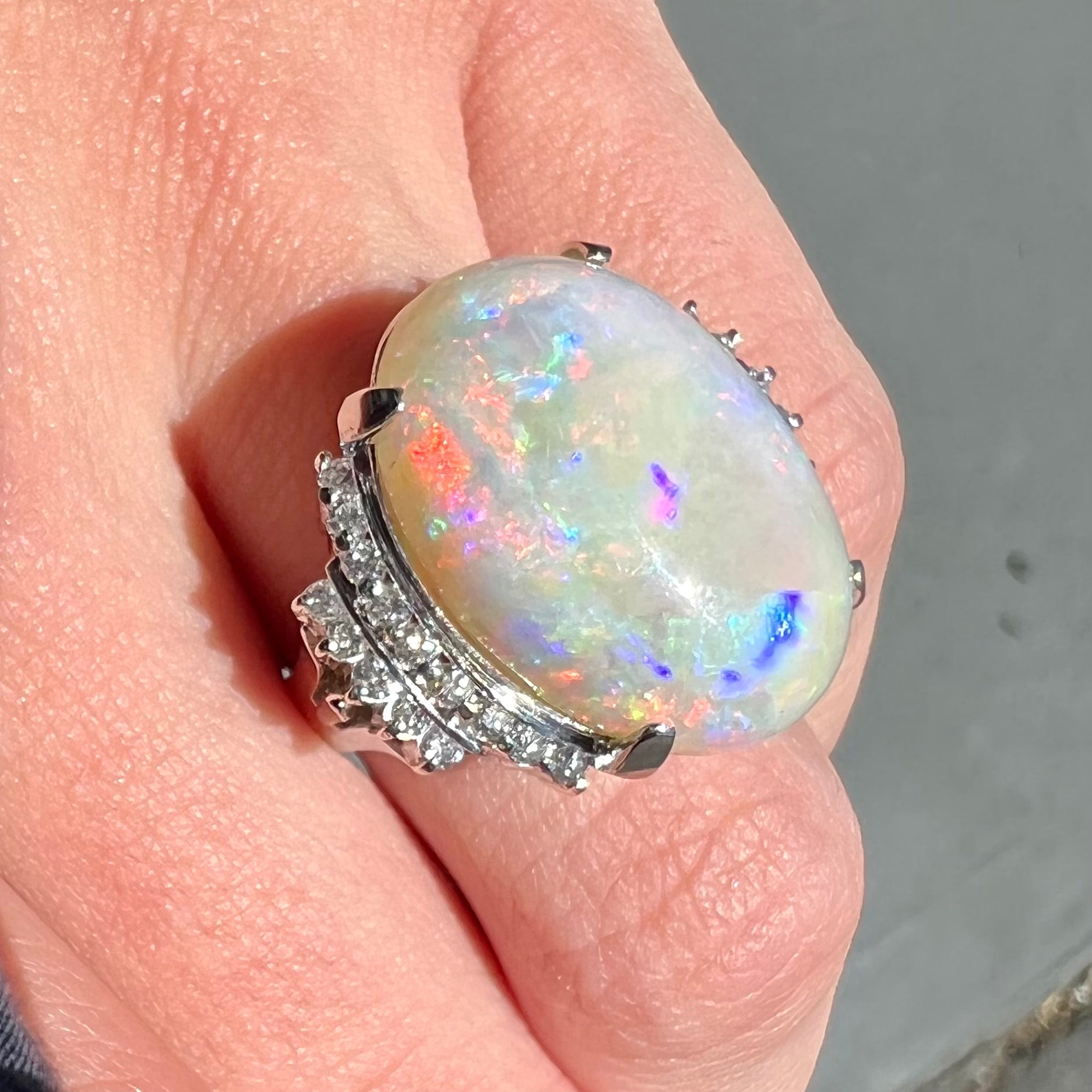 An oval cabochon cut Coober Pedy, Australian opal prong set in a platinum ring with round cut diamonds.