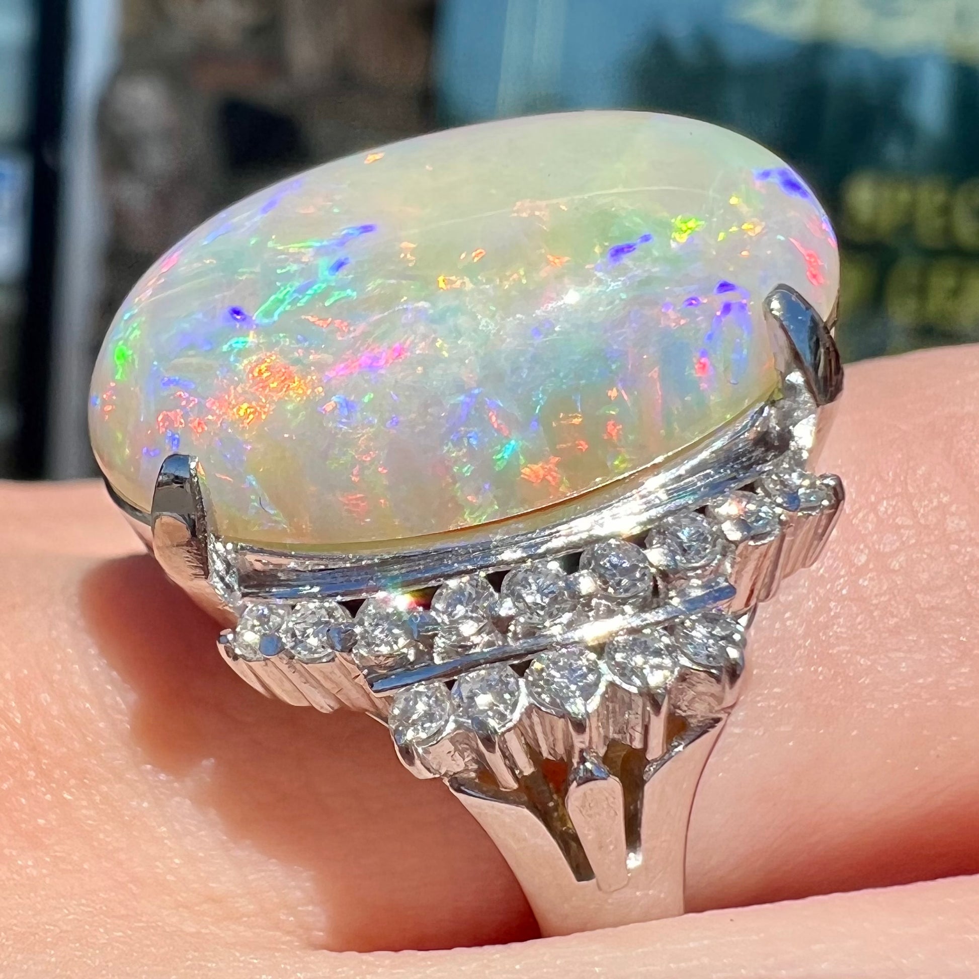 An oval cabochon cut Coober Pedy, Australian opal prong set in a platinum ring with round cut diamonds.