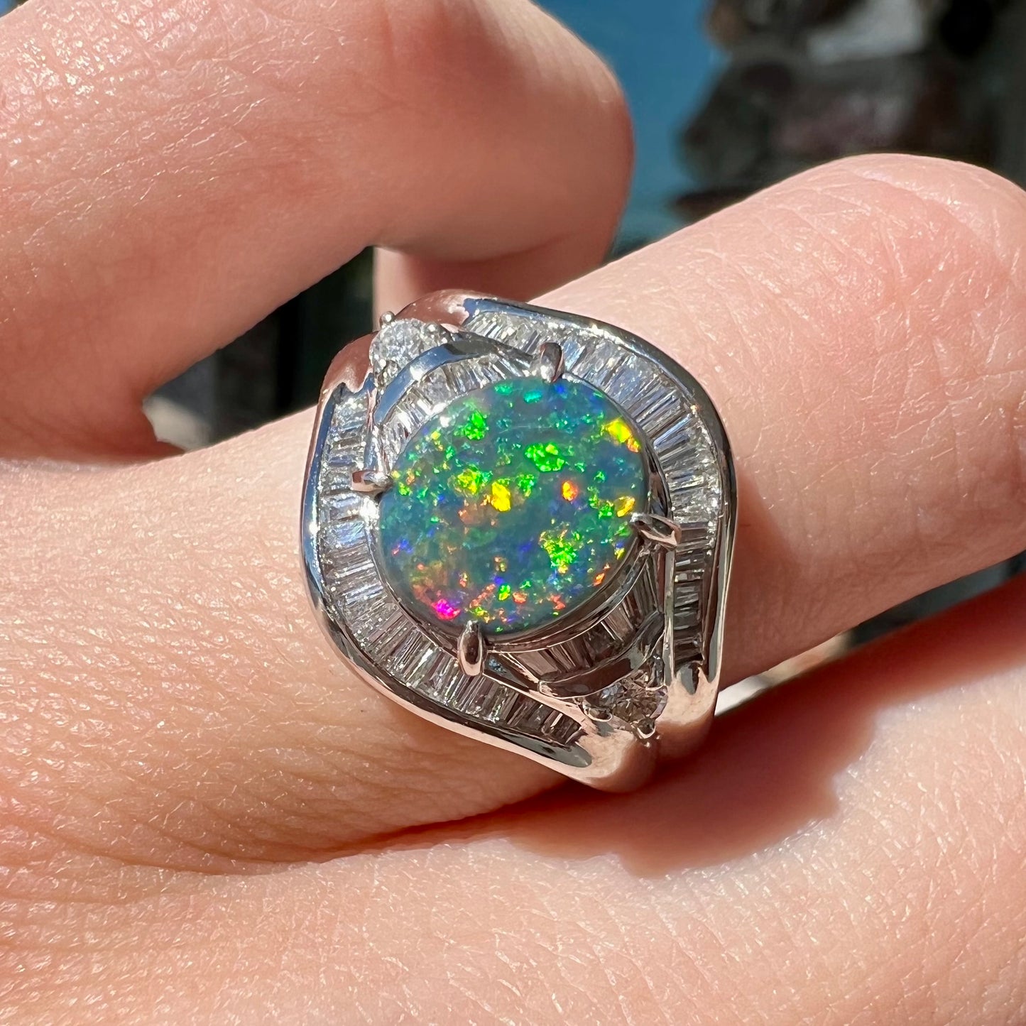 A platinum Lightning Ridge black opal ring set with baguette cut diamonds.  The opal is an oval cabochon cut.
