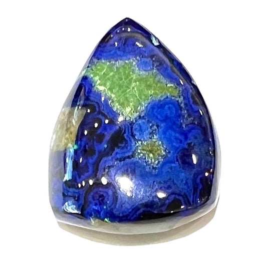 A loose pear shape cabochon cut blue azurite stone with green pseudomalachite inclusions.