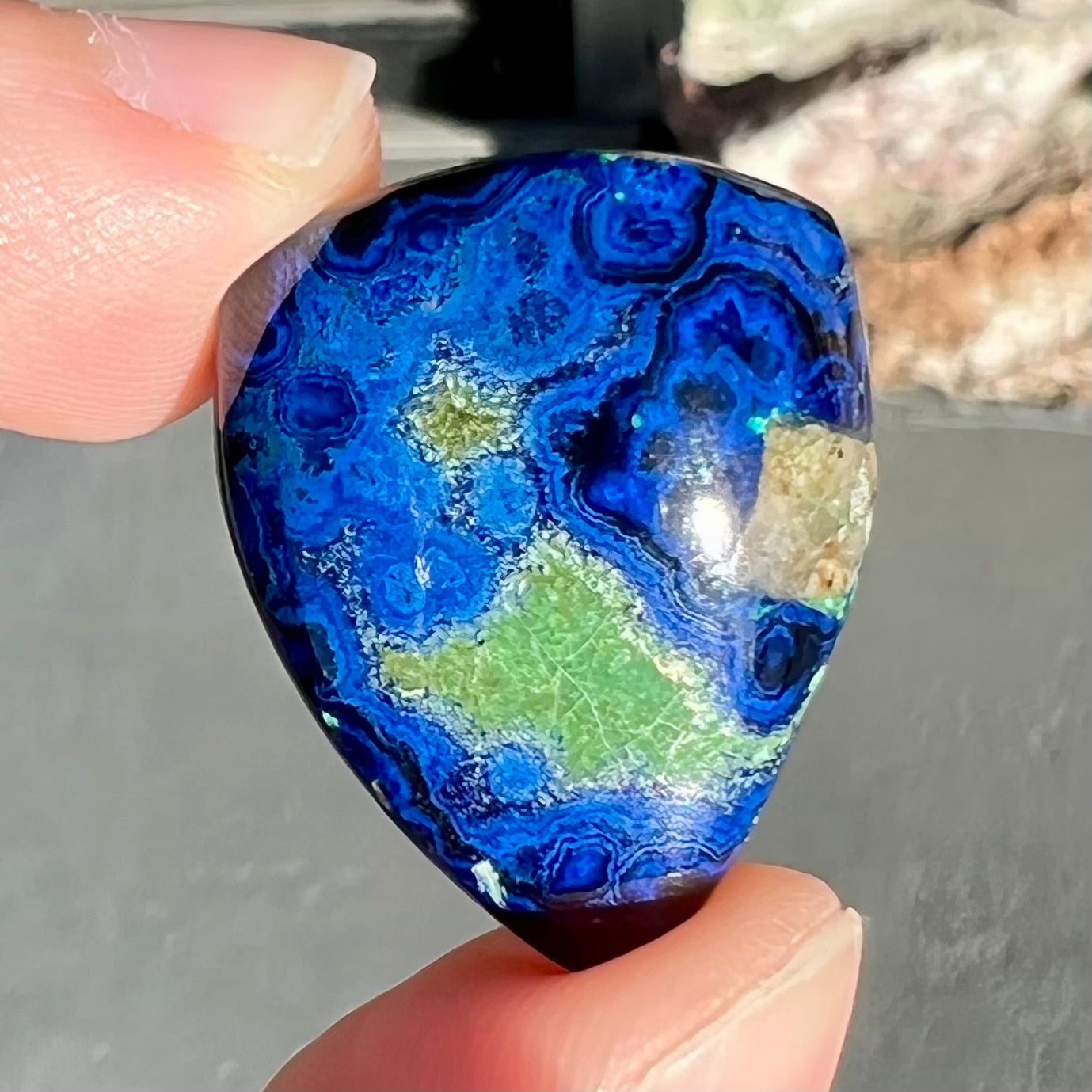 A loose pear shape cabochon cut blue azurite stone with green pseudomalachite inclusions.