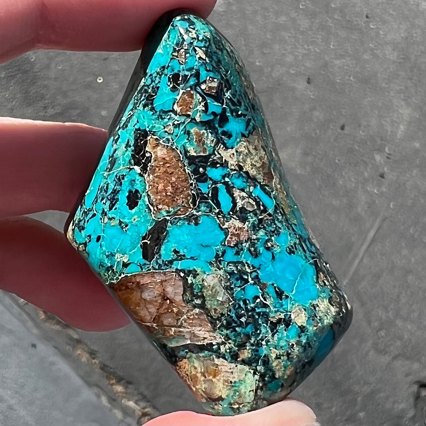 A loose polished chrysocolla stone with malachite inclusions.