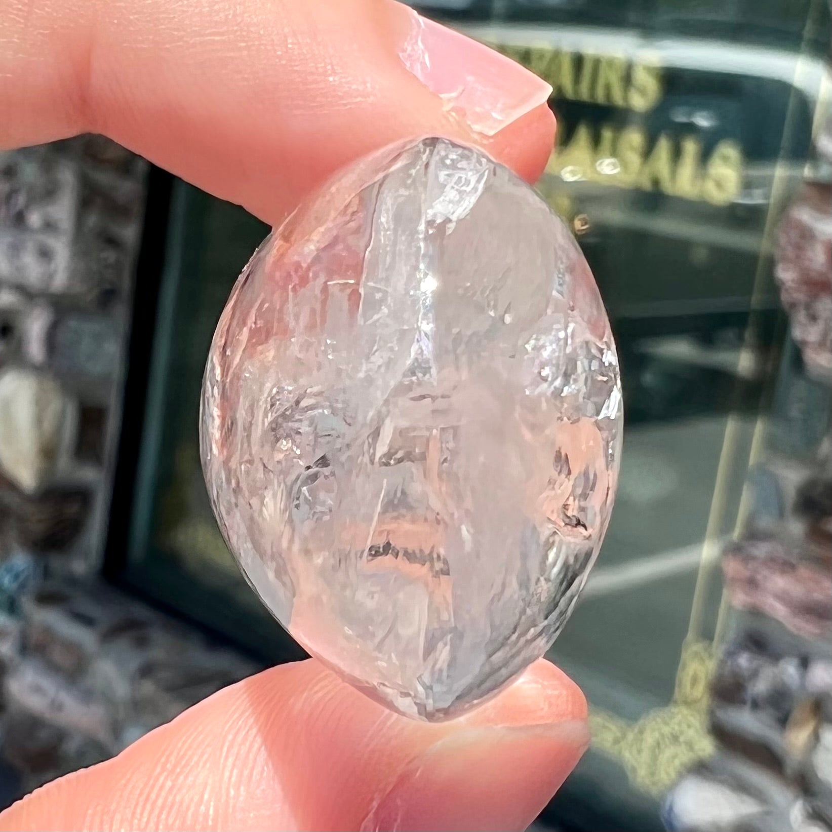 A polished clear quartz with two liquid enhydro inclusions around a solid phantom crystal inclusion.