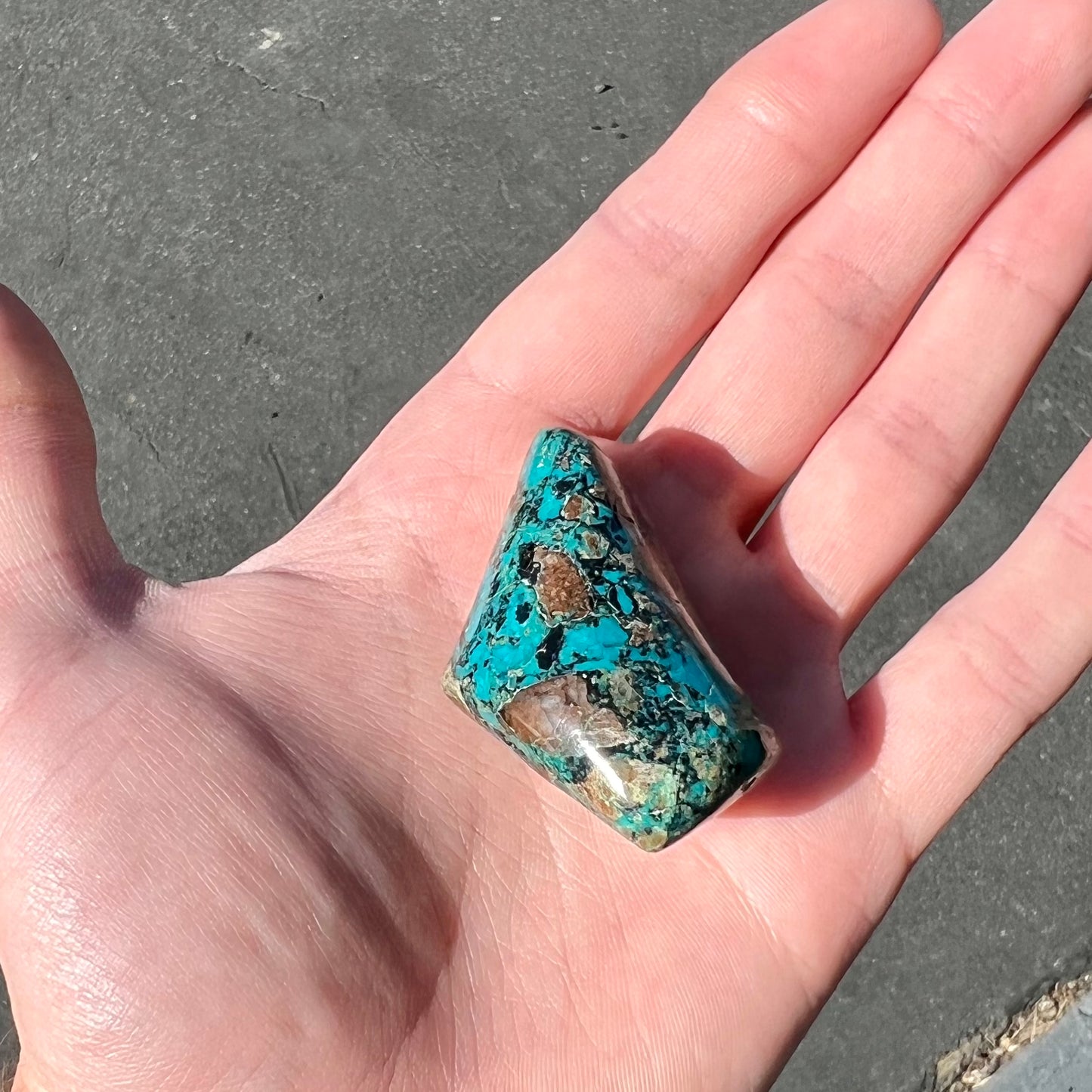 A loose polished chrysocolla stone with malachite inclusions.