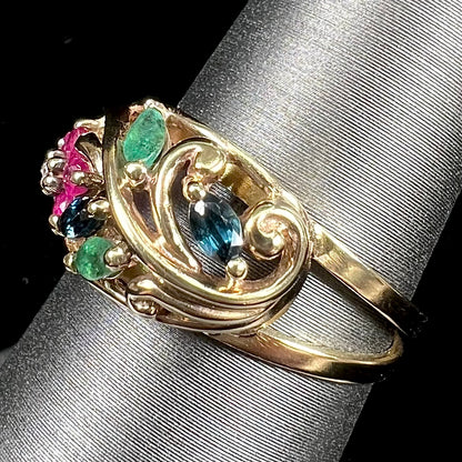 A yellow gold ladies' ring featuring the motif of a flower with leaves set with emeralds, rubies, sapphires, and a  diamond.