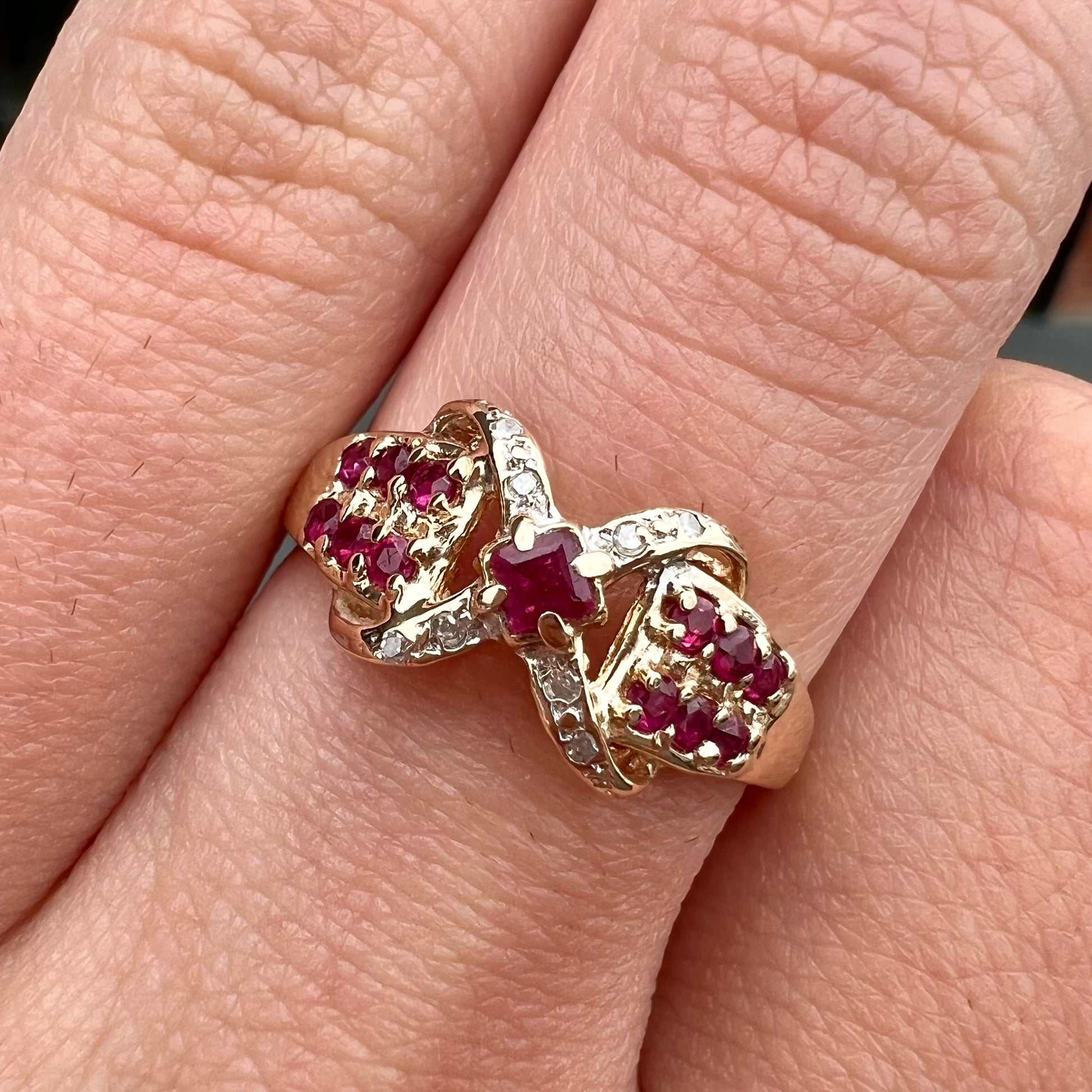 A yellow gold princess cut ruby ring set with round ruby and diamond accents.