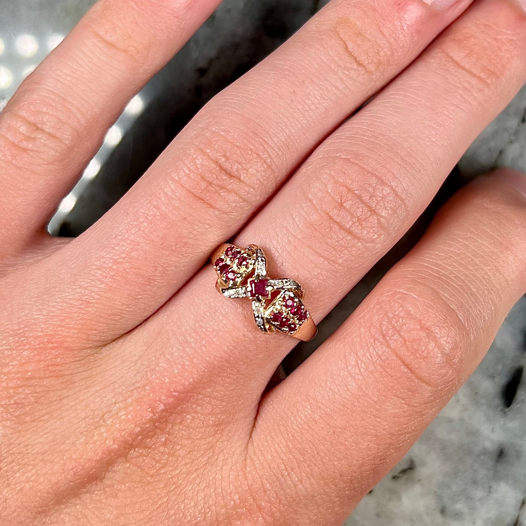 A yellow gold princess cut ruby ring set with round ruby and diamond accents.