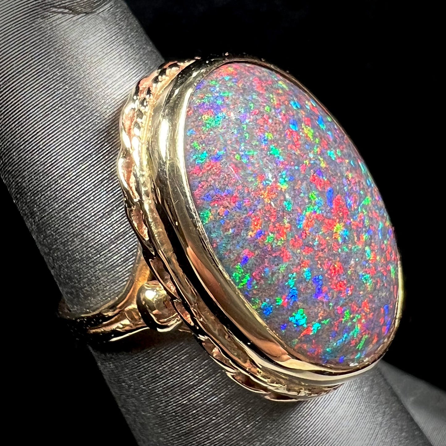 A bright black Andamooka opal that displays a pinfire pattern set in a vintage-style yellow gold bezel ring.