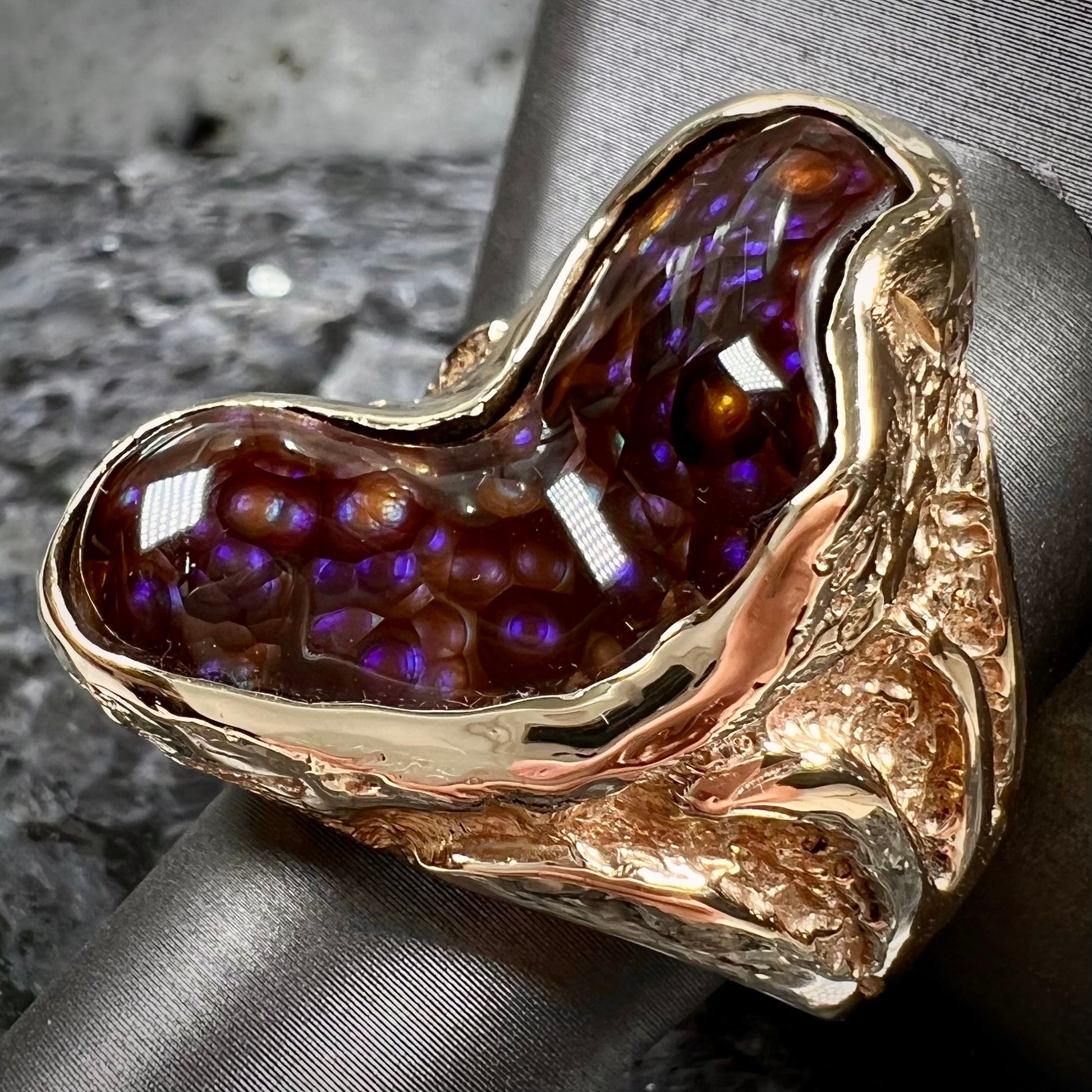 A men's Deer Creek fire agate solitaire ring cast in yellow gold.  The stone is predominantly purple.