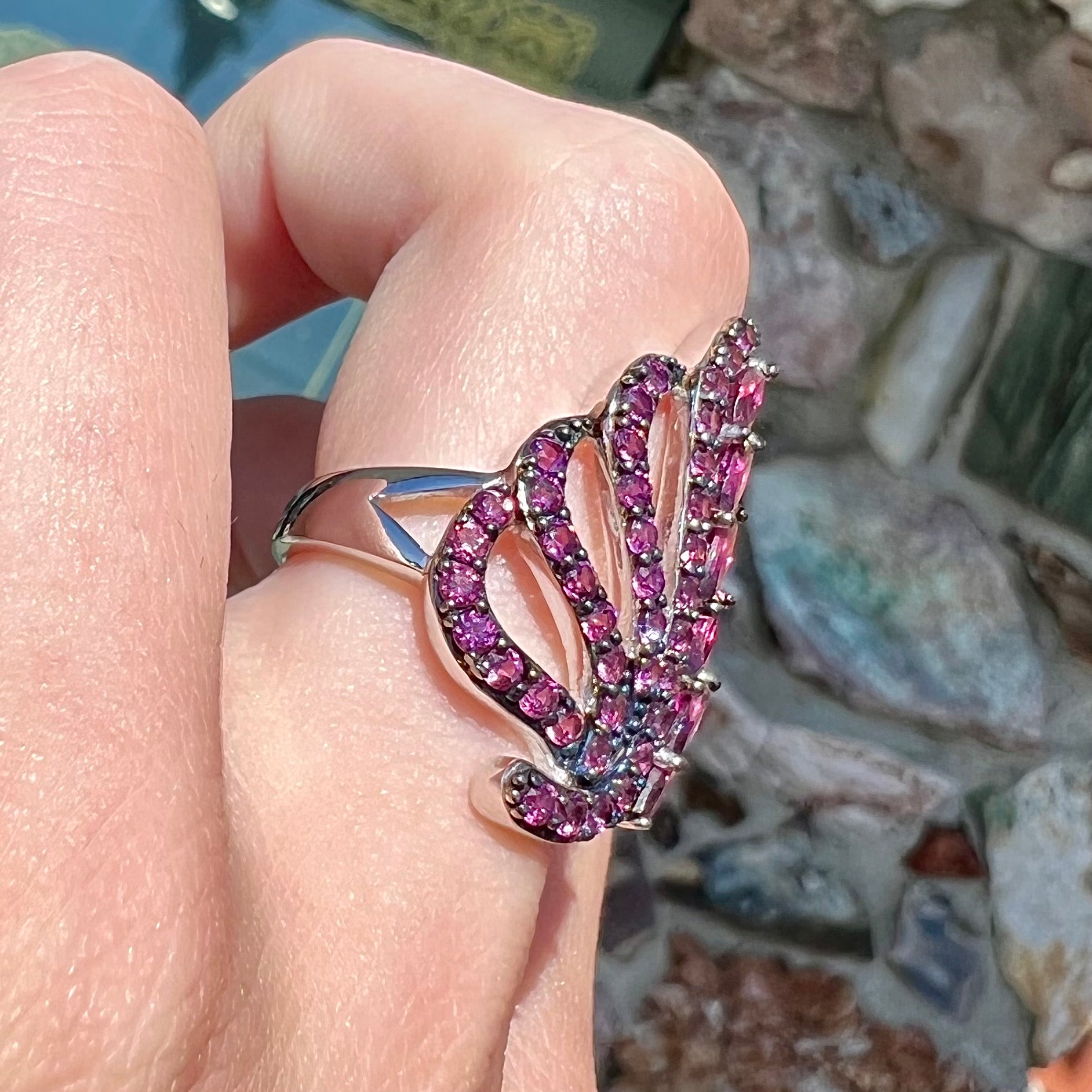 A sterling silver, feather shaped ring set with round and marquise cut rhodolite garnet stones.