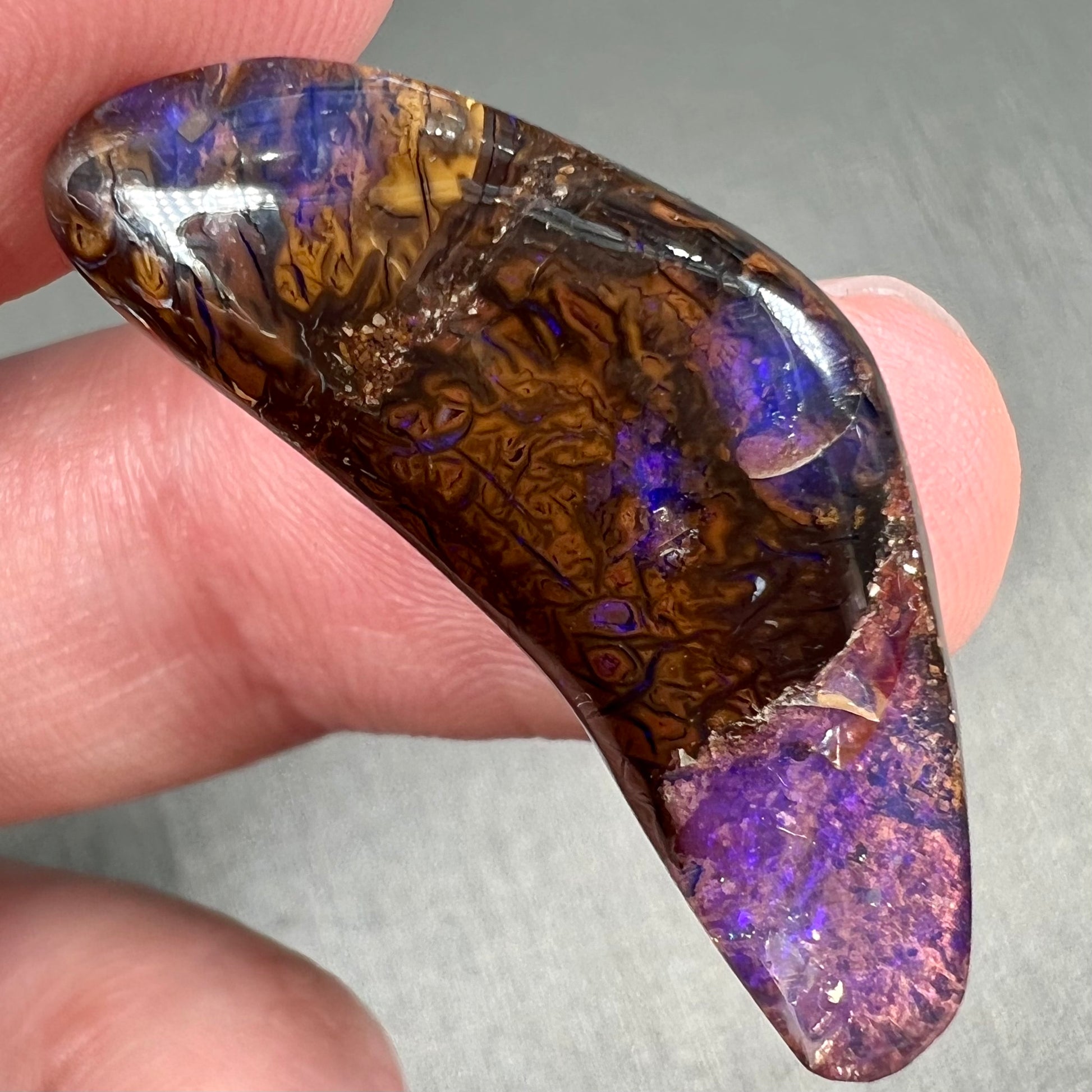 A loose boomerang shaped purple boulder opal stone from Quilpie, Australia.