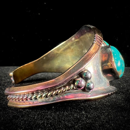 A men's Navajo three stone turquoise cuff bracelet handmade by artist, Dean Brown.  The silver has an iridescent purple patina.