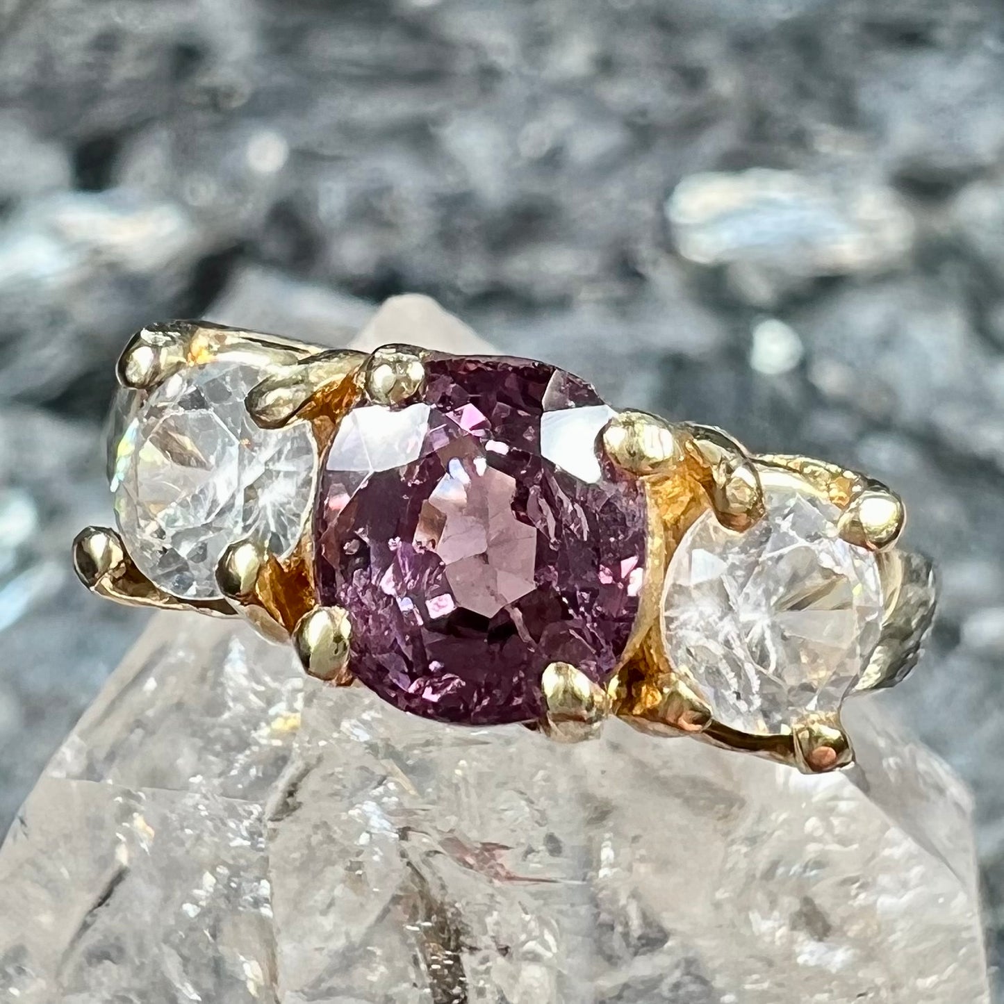 A yellow gold three stone ring set with two round cut white zircons and one cushion cut purple spinel.