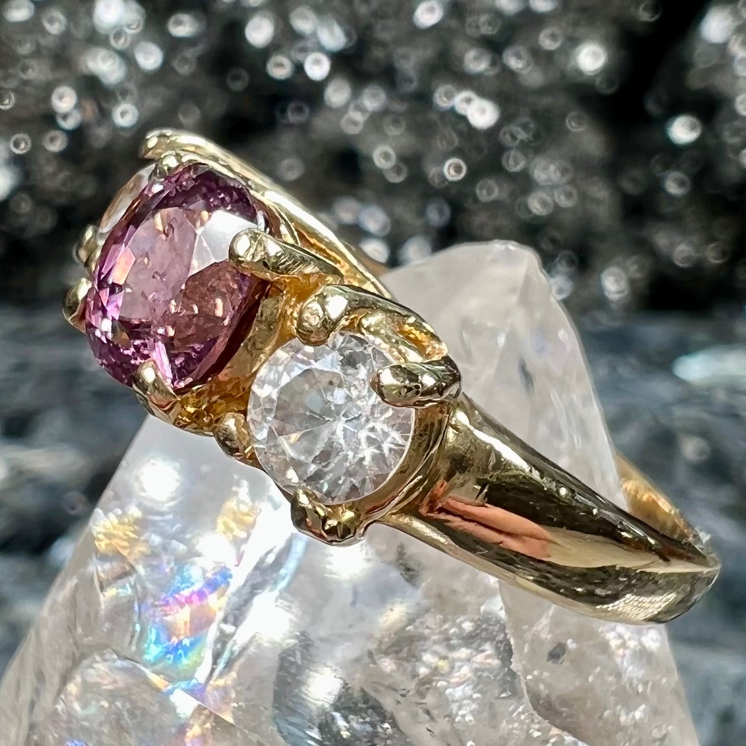 A yellow gold three stone ring set with two round cut white zircons and one cushion cut purple spinel.