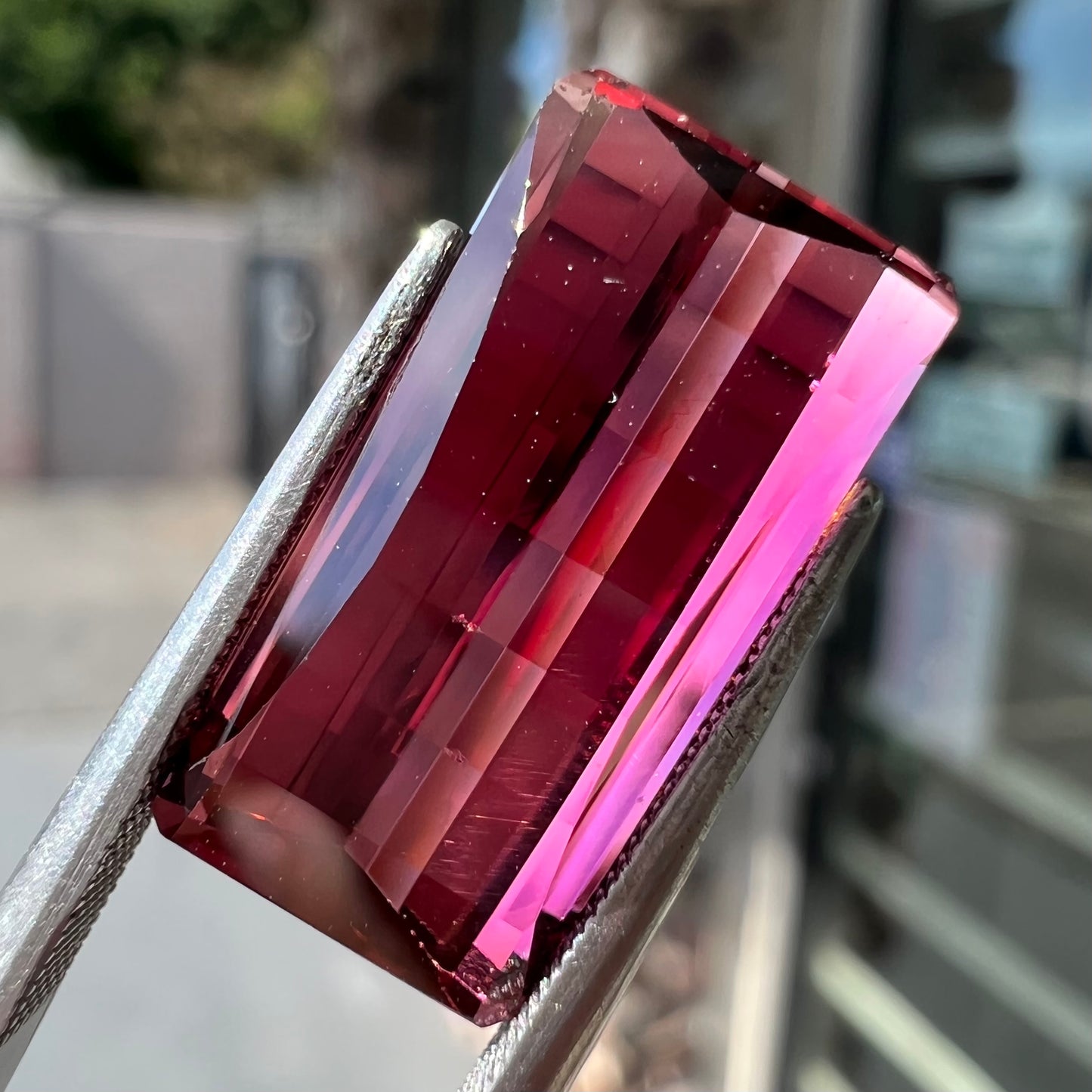 A loose, fantasy cut reddish colored tourmaline.  The cut reflects light in a way that resembles digital pixels on a screen.
