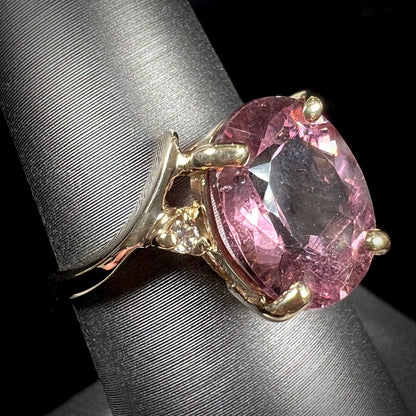 A ladies' yellow gold, faceted oval cut purple tourmaline ring set with diamond accents.
