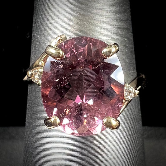 A ladies' yellow gold, faceted oval cut purple tourmaline ring set with diamond accents.