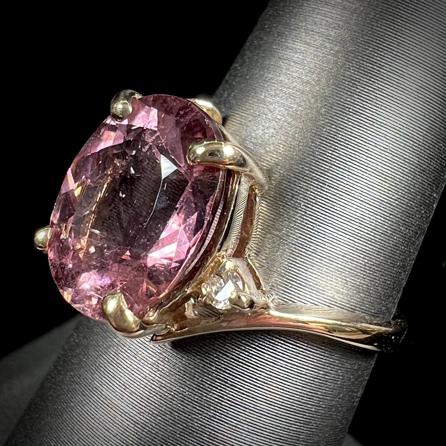 A ladies' yellow gold, faceted oval cut purple tourmaline ring set with diamond accents.