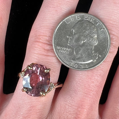 A ladies' yellow gold, faceted oval cut purple tourmaline ring set with diamond accents.
