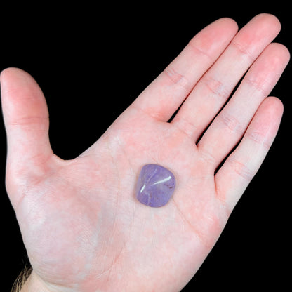 A tumbled turkiyenite jade stone from Bursa, Turkey.  The rock is purple with red speckles.