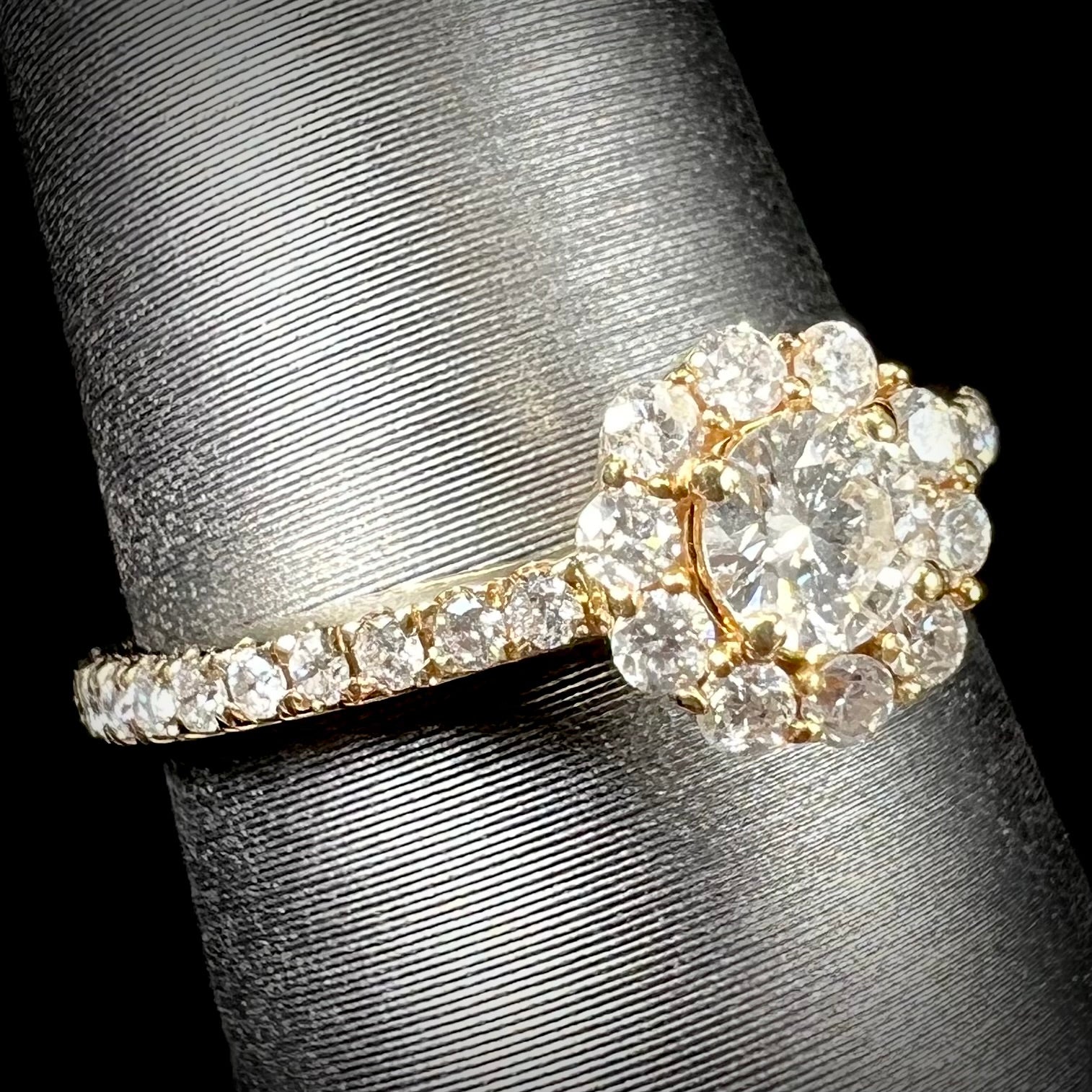 A ladies' diamond halo engagement ring cast in yellow gold.  The center stone is a 0.19ct round cut natural diamond.