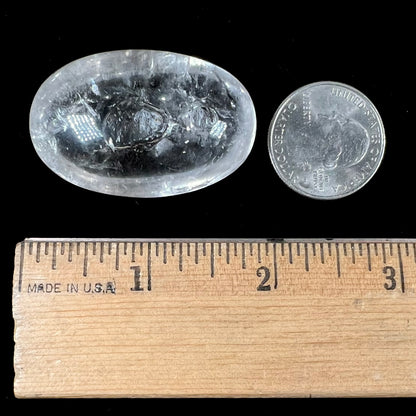 A polished clear quartz with two liquid enhydro inclusions around a solid phantom crystal inclusion.