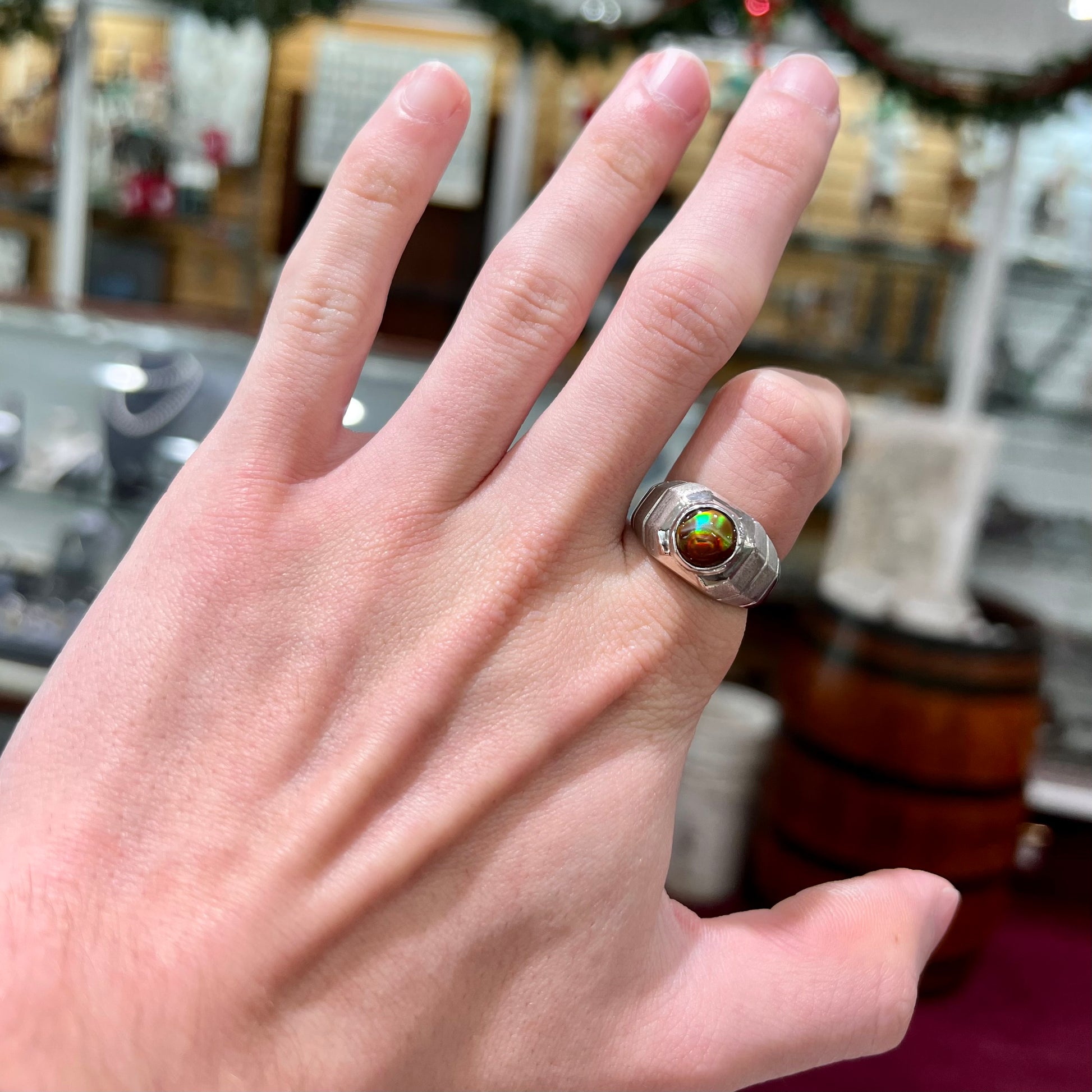 A round cabochon cut red and green fire agate set in a brushed metal white gold men's ring.