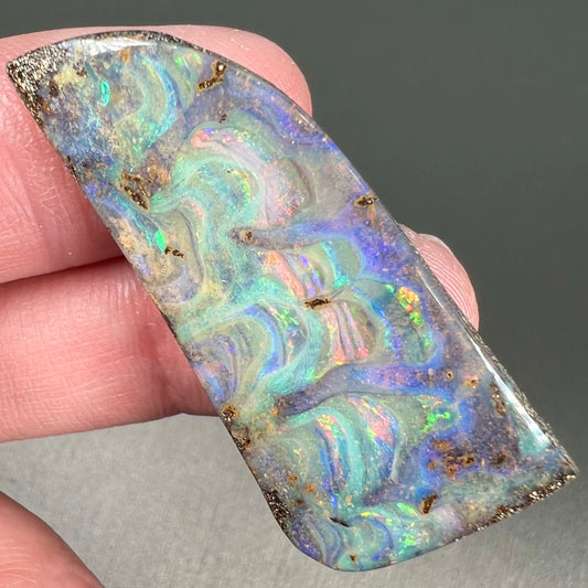 A loose, freeform cut, natural boulder opal stone from Quilpie, Australia.