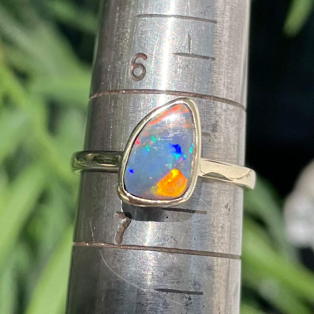 A handmade yellow gold solitaire ring bezel set with a Lightning Ridge red-on-black harlequin opal.