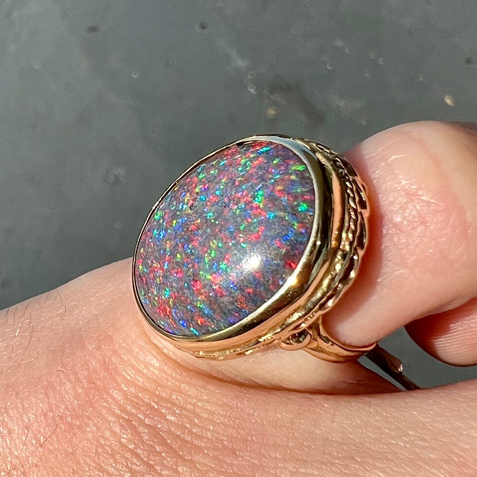 A bright black Andamooka opal that displays a pinfire pattern set in a vintage-style yellow gold bezel ring.