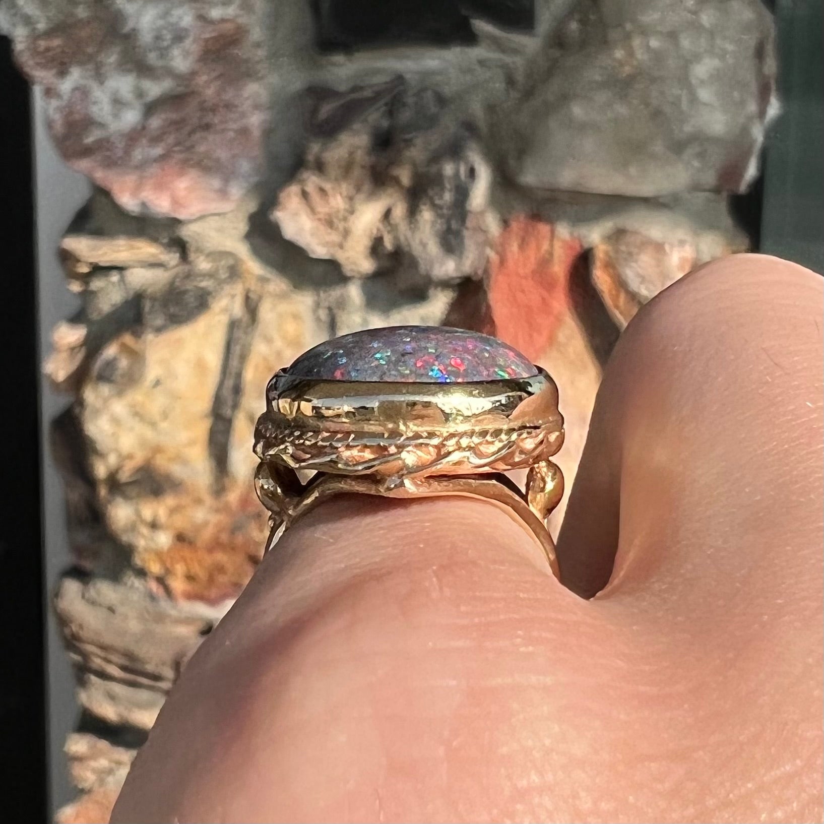 A bright black Andamooka opal that displays a pinfire pattern set in a vintage-style yellow gold bezel ring.