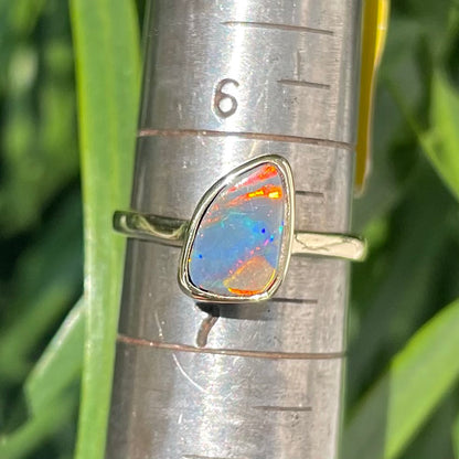 A handmade yellow gold solitaire ring bezel set with a Lightning Ridge red-on-black harlequin opal.