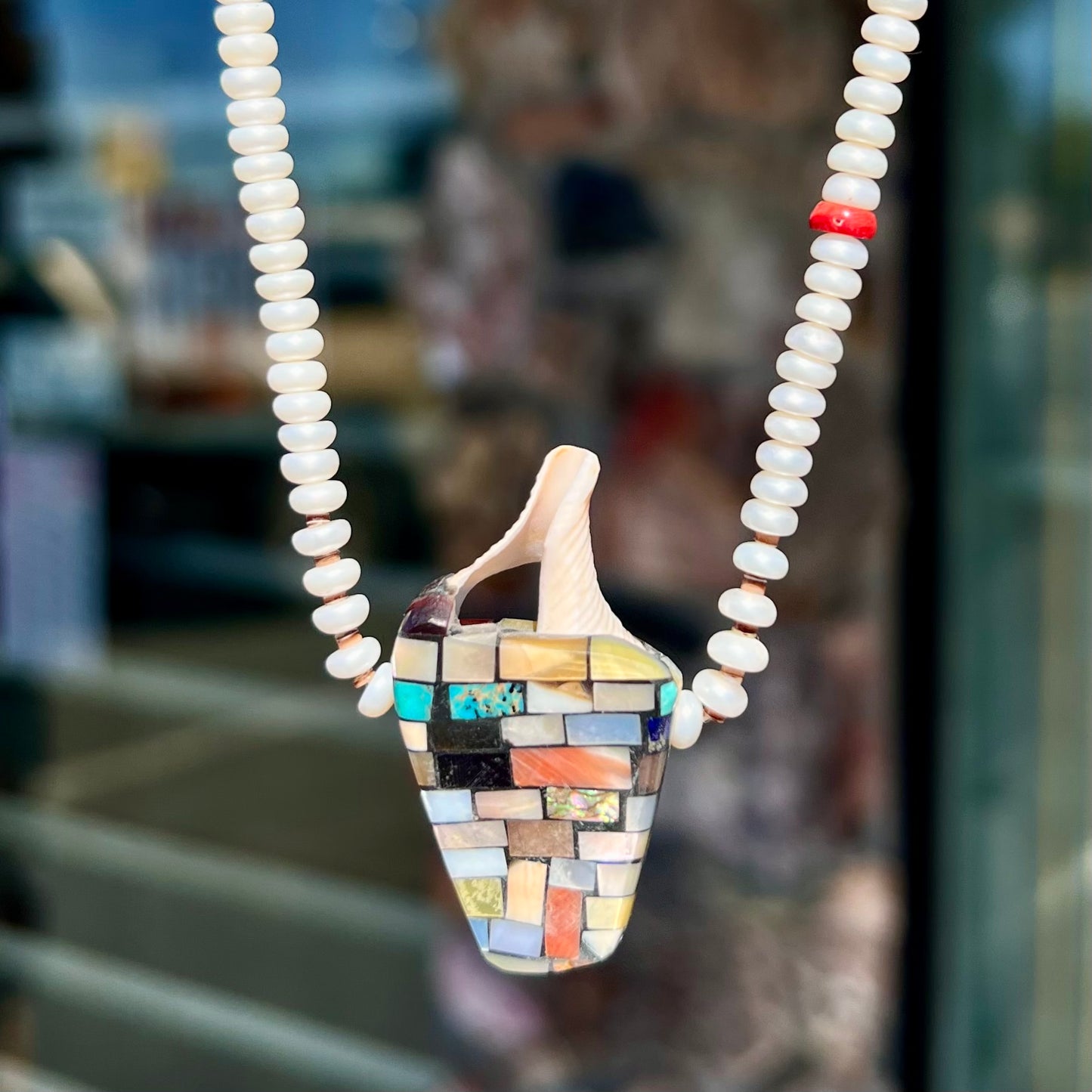 A seashell necklace that has been inlaid with spiny oyster and mother of pearl shell on a pearl bead necklace by Charlene Reano.