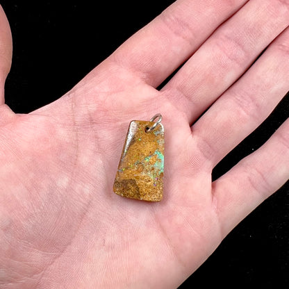 A drilled boulder opal stone with a sterling silver ring through the hole to be worn as a pendant.