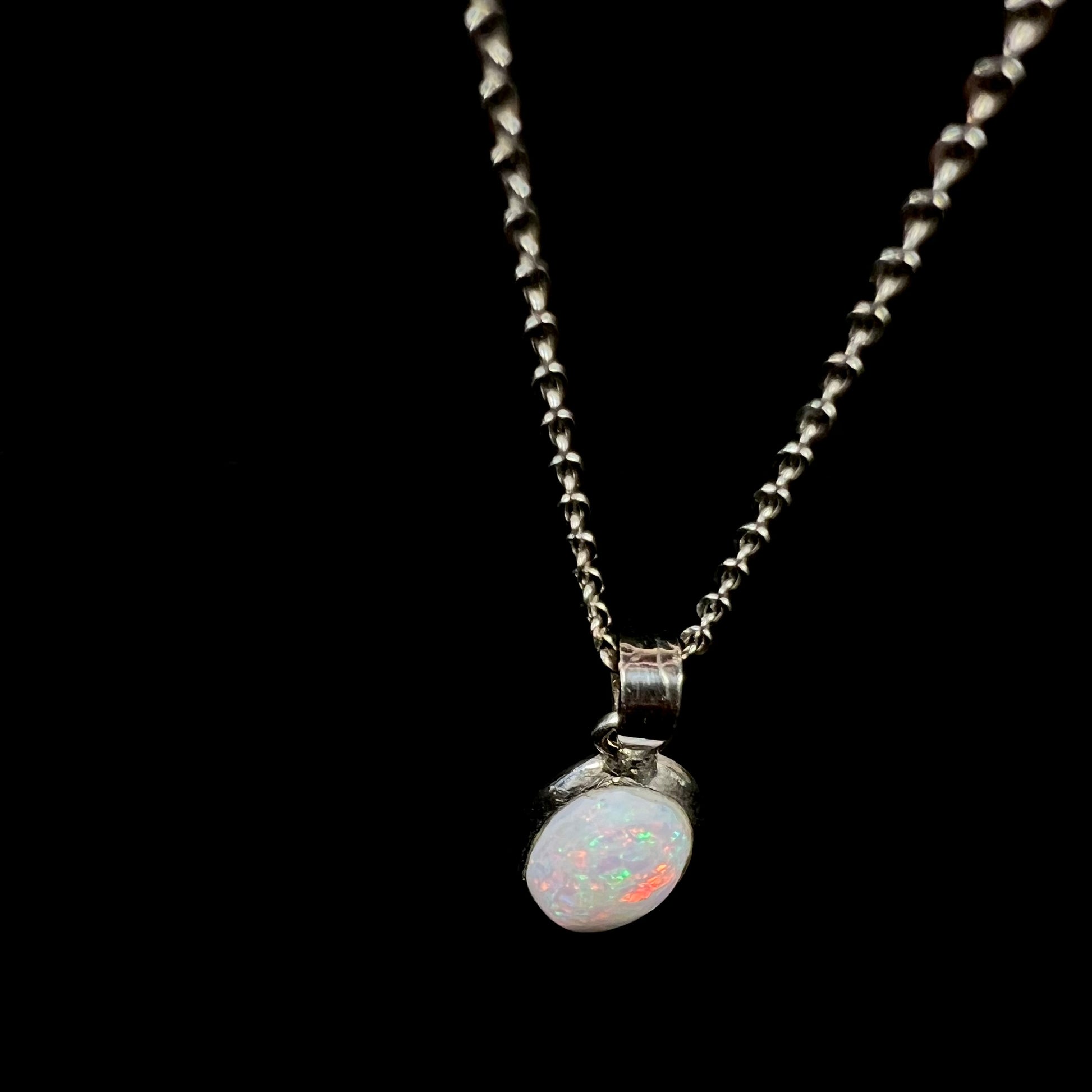 A ladies' adjustable sterling silver necklace bezel set with a natural, oval cabochon cut white crystal opal.
