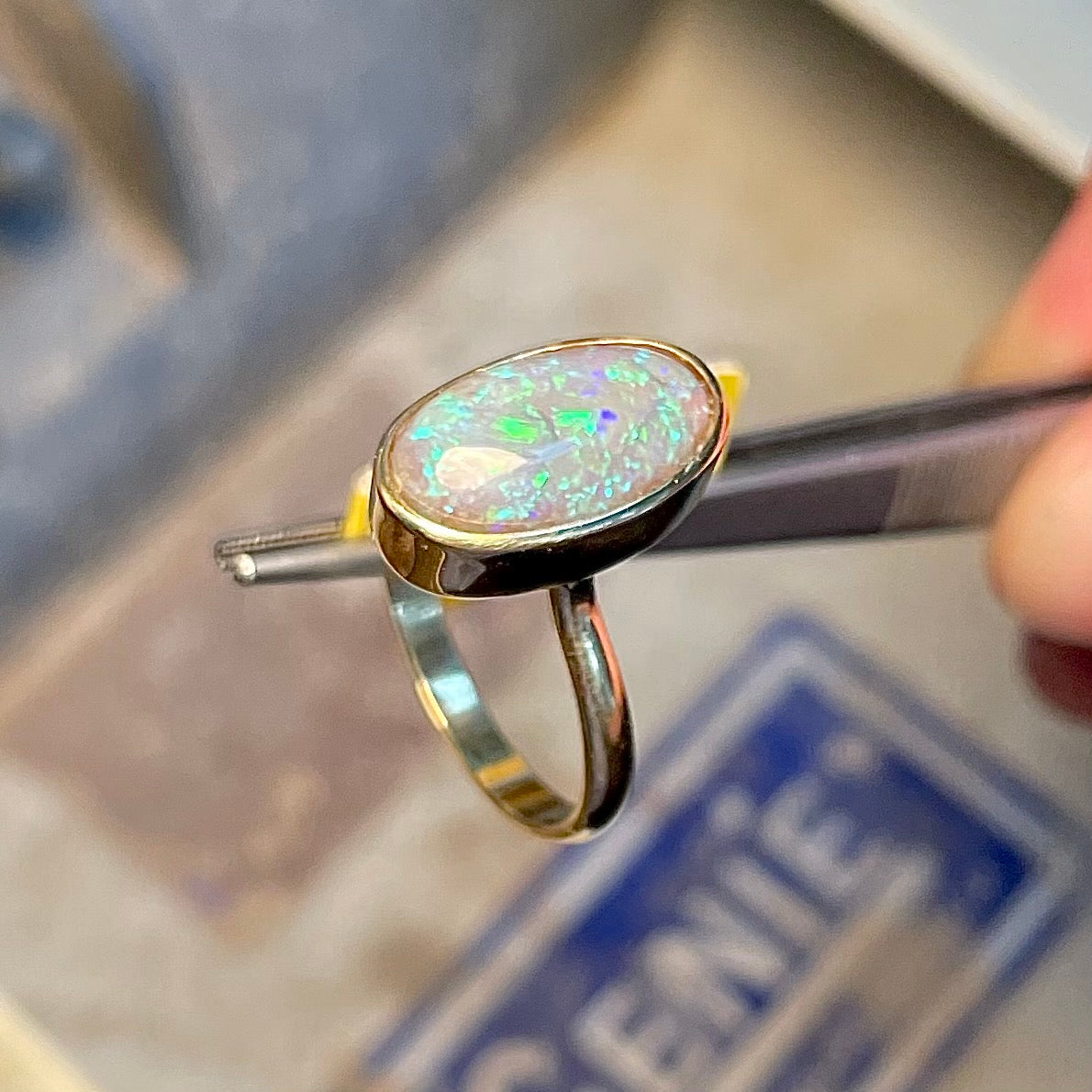 A simple yellow gold solitaire ring with a bezel set Lightning Ridge black crystal opal from Australia.