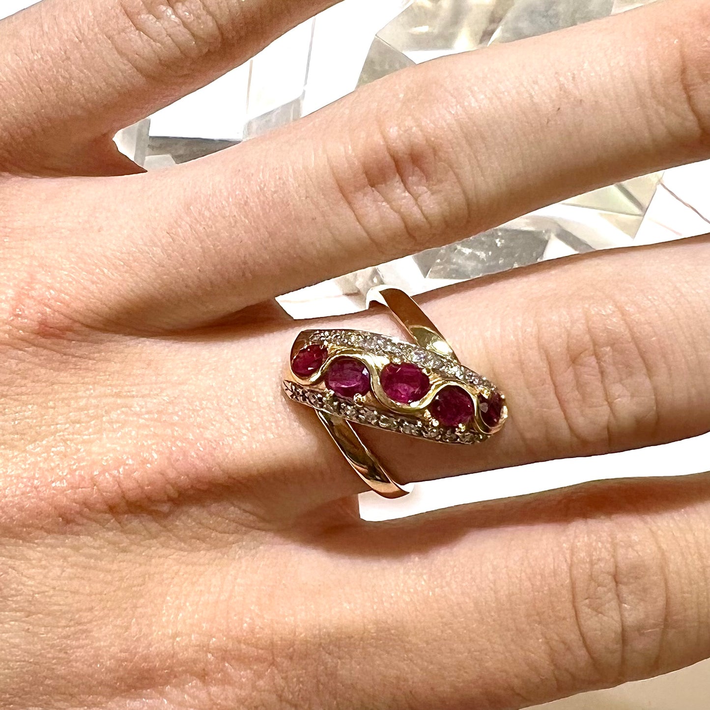 A custom freeform design yellow gold twisted shank ring set with five oval cut rubies and small round diamonds.