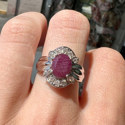 A natural, faceted oval cut ruby ring cast in sterling silver and set with cubic zirconia accents.