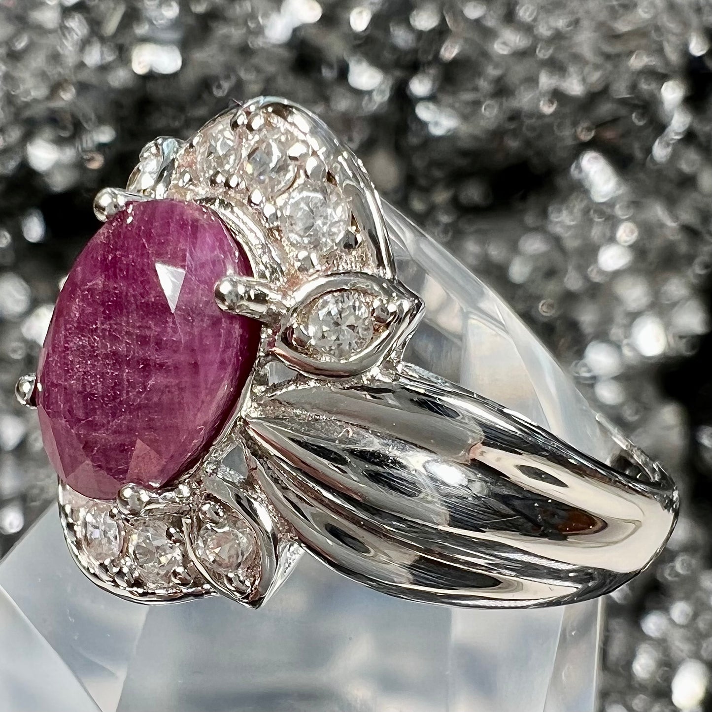 A natural, faceted oval cut ruby ring cast in sterling silver and set with cubic zirconia accents.