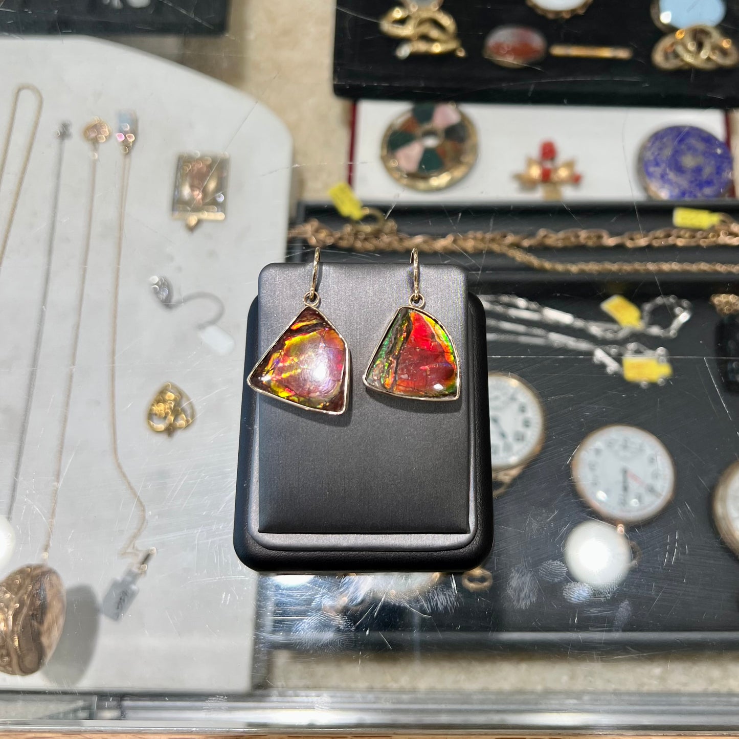 Yellow gold French wire dangle earrings bezel set with two polished freeform cut red ammolite fossils.