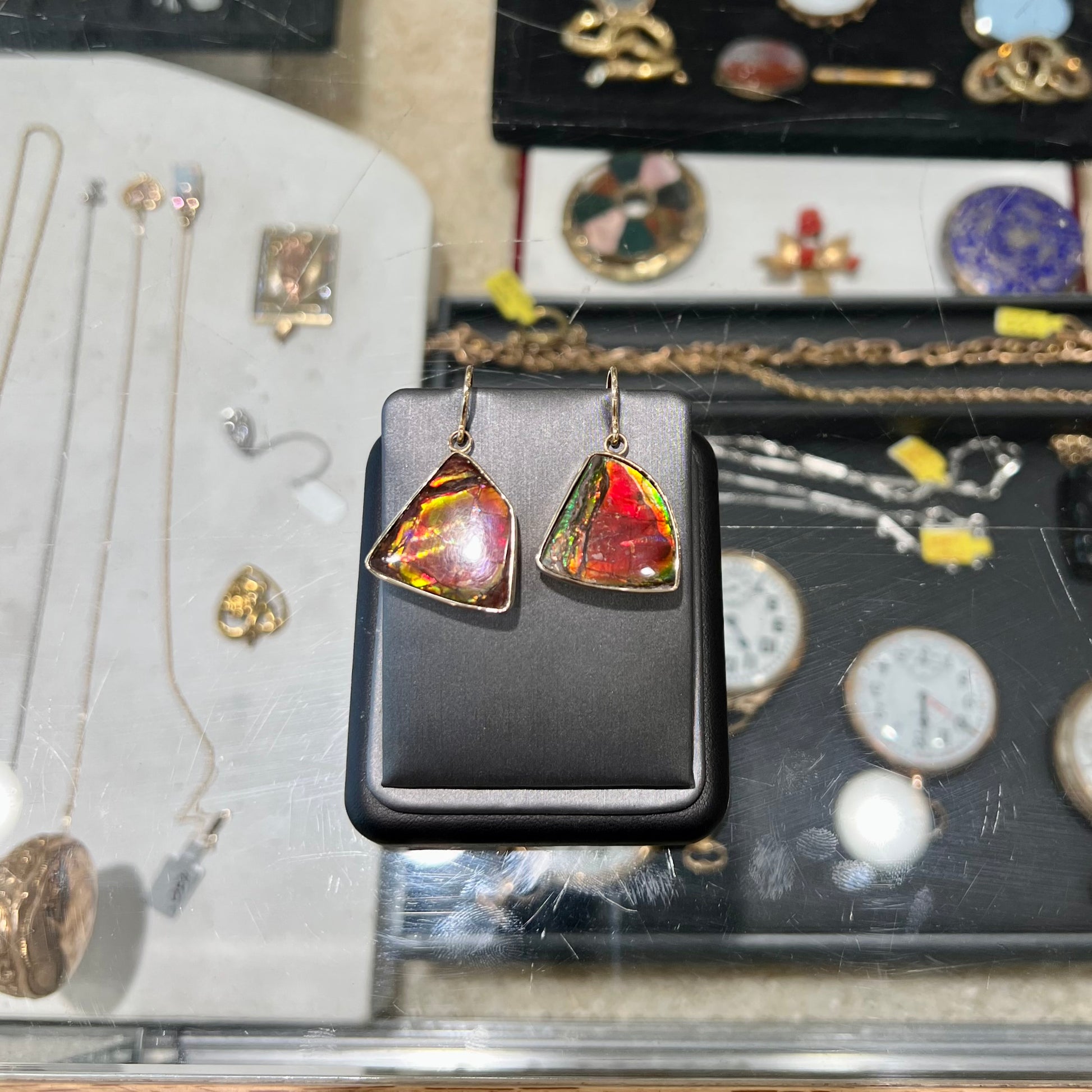 Yellow gold French wire dangle earrings bezel set with two polished freeform cut red ammolite fossils.