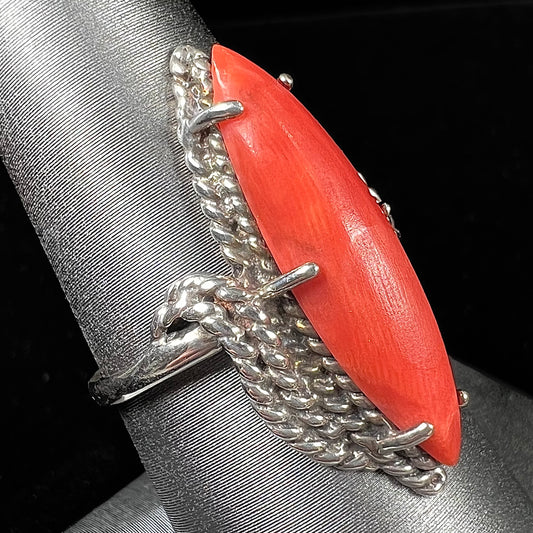 A prong-set silver ring set with a red marquise cut coral.