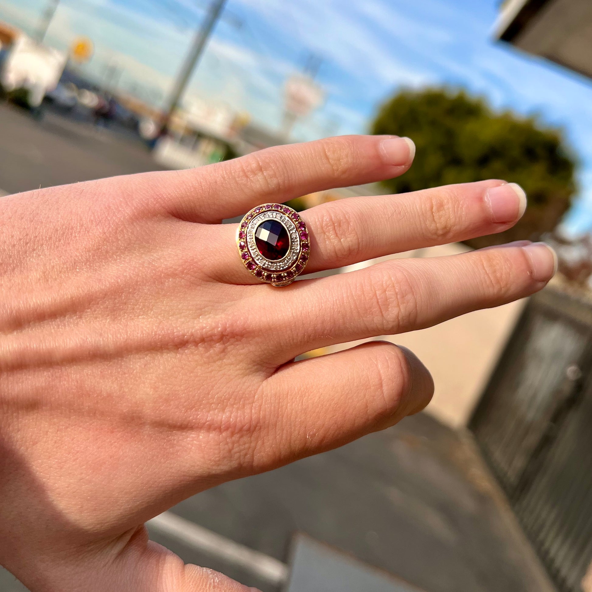 A yellow gold garnet and diamond halo ring set with a checkerboard cut rhodolite garnet center stone.