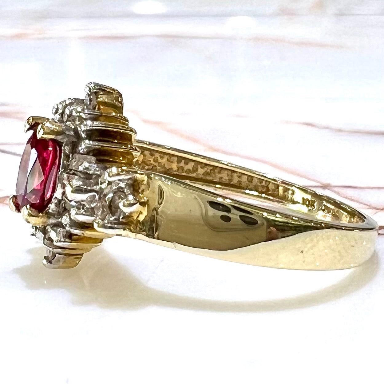 A yellow gold ring set with an oval cut red spinel and diamond rounds and baguettes.