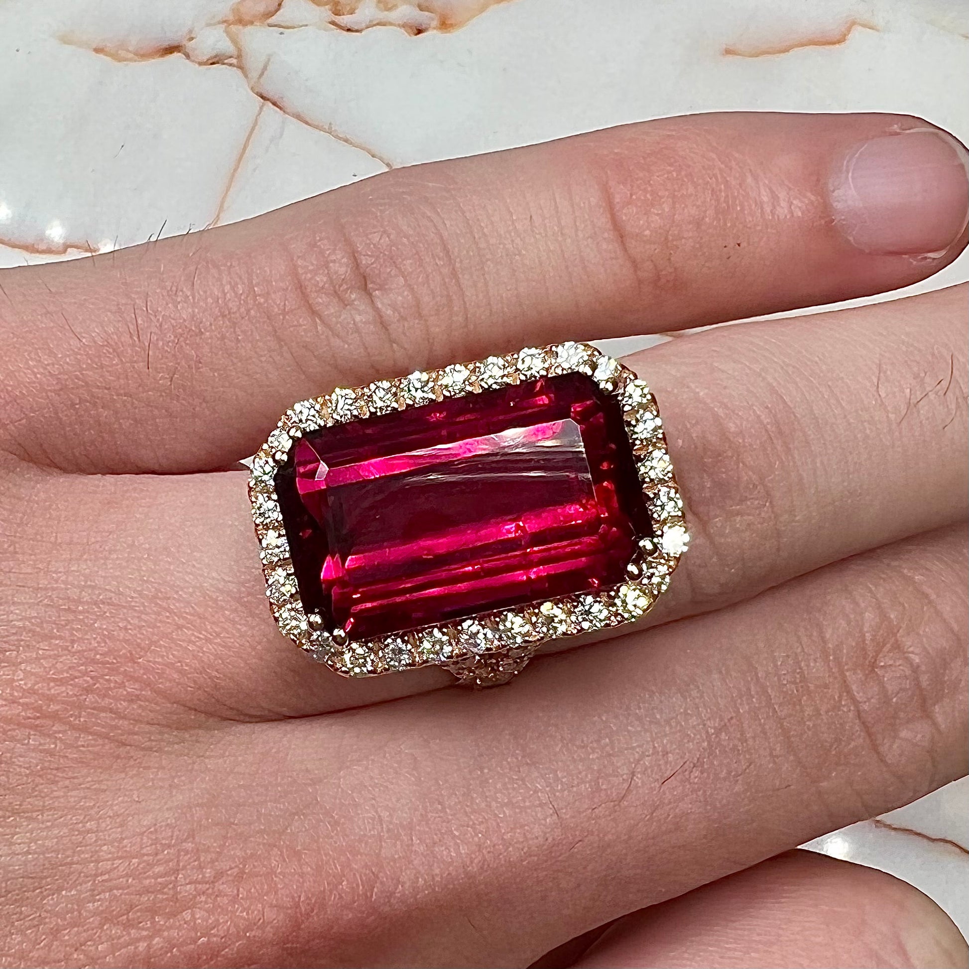 Red emerald cut rubellite tourmaline gemstone set with near flawless round cut diamonds in rose gold.