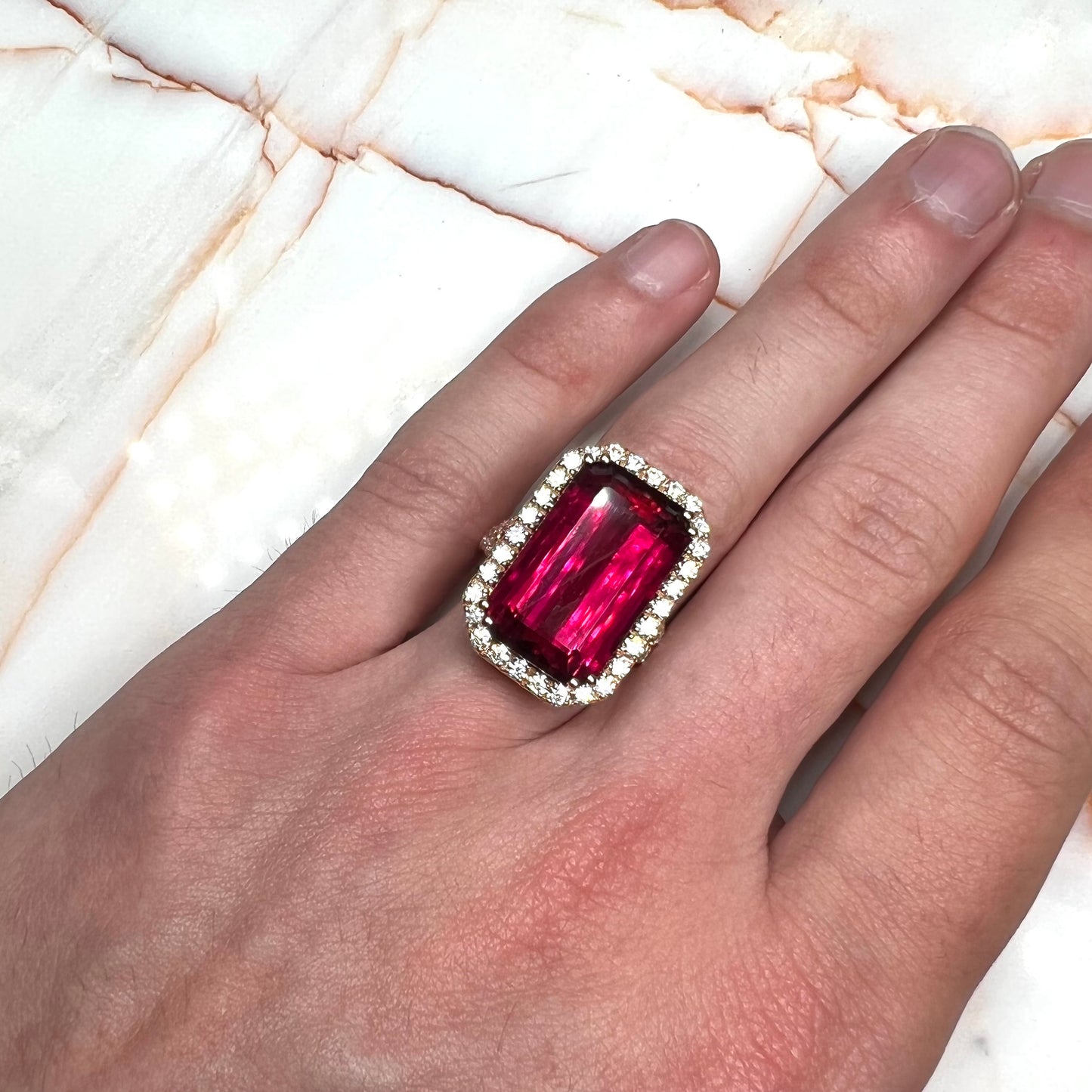 Red emerald cut rubellite tourmaline gemstone set with near flawless round cut diamonds in rose gold.