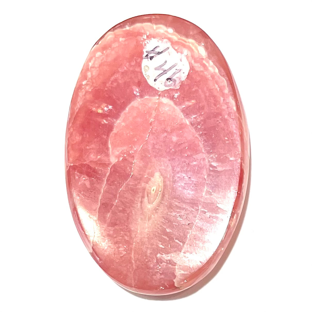 An oval cabochon cut pink rhodochrosite stone.