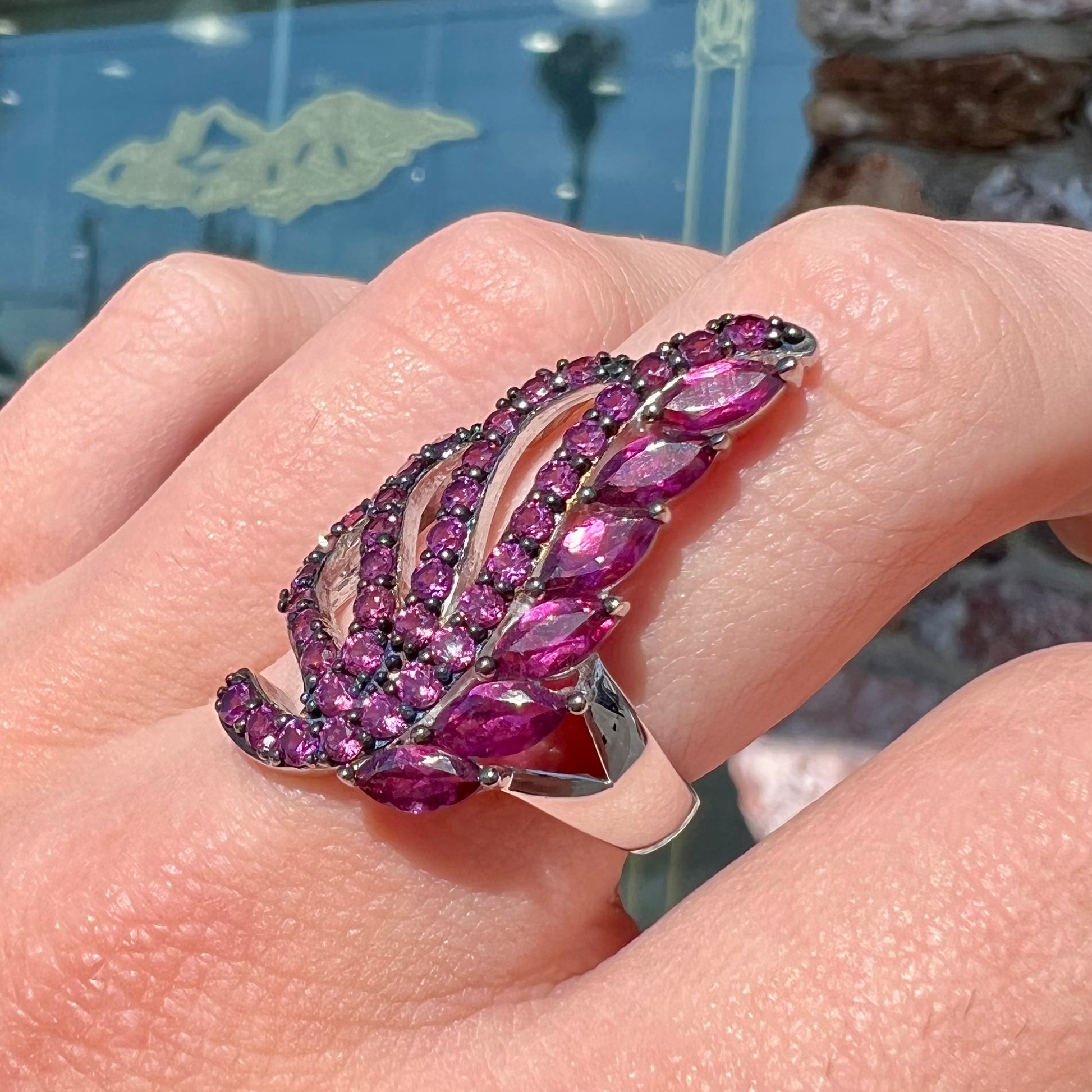 A sterling silver, feather shaped ring set with round and marquise cut rhodolite garnet stones.