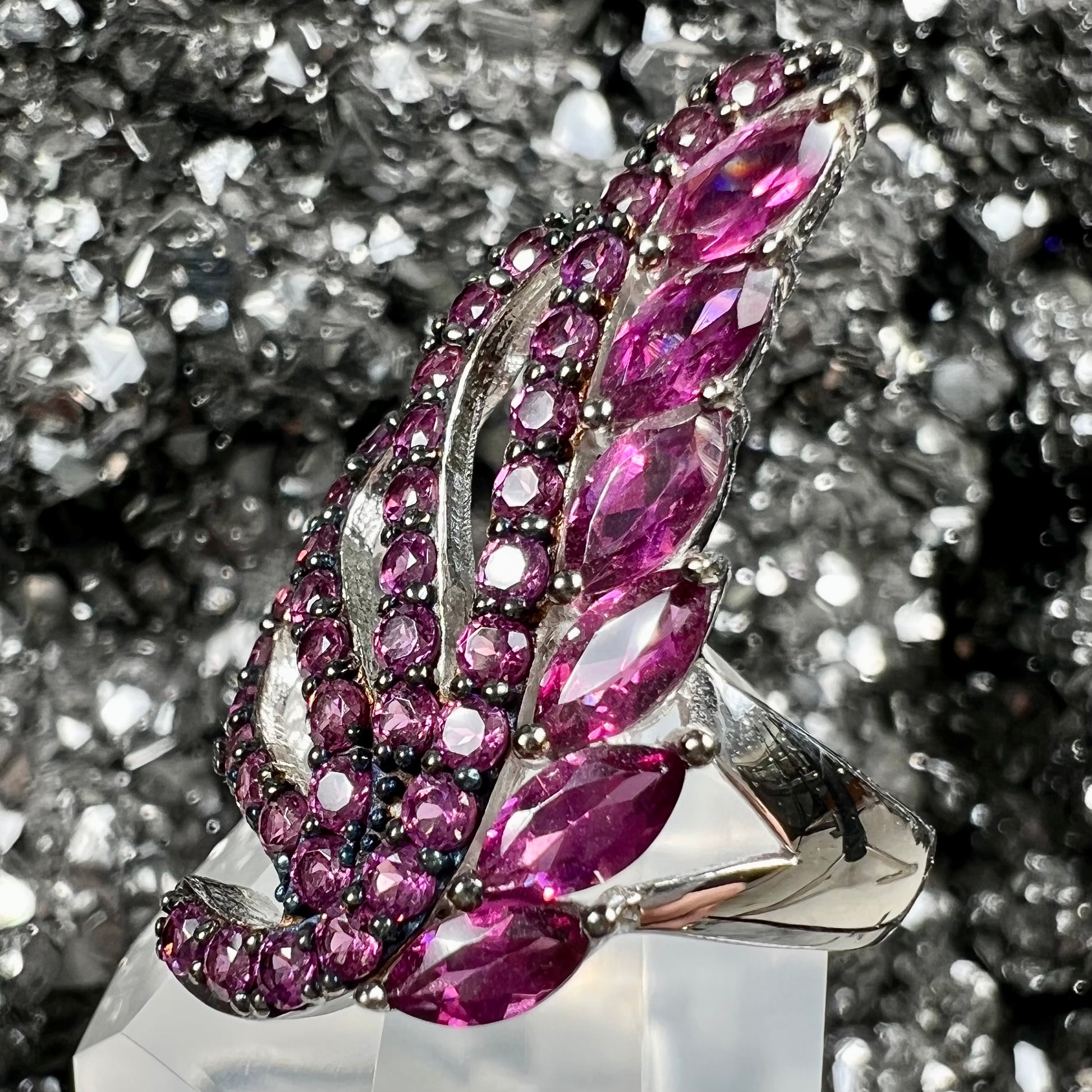 A sterling silver, feather shaped ring set with round and marquise cut rhodolite garnet stones.